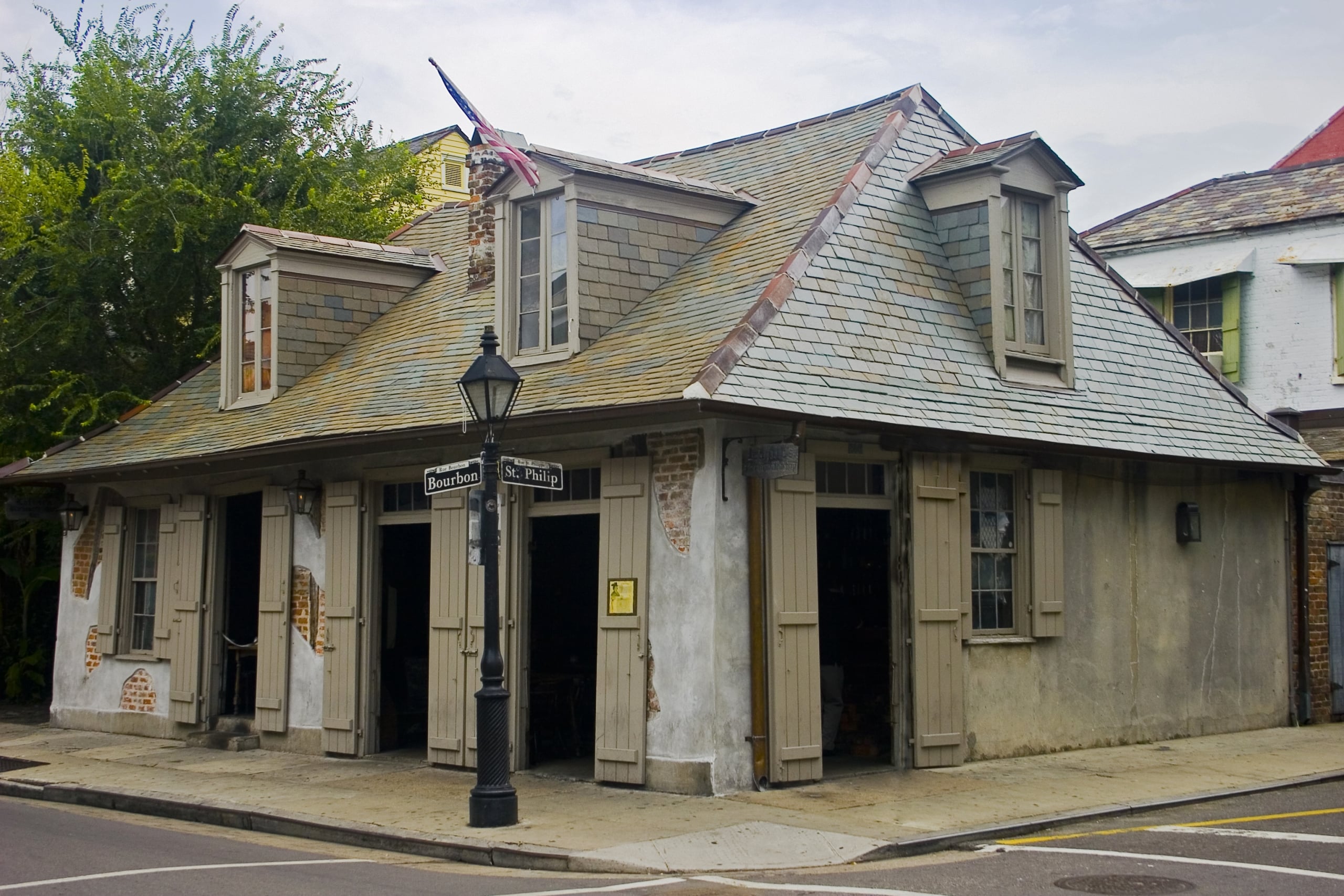 Corner building on Bourbon and St Philip Streets, New Orleans French Quarter, with historic stucco, shutters, and a unique slate roof.