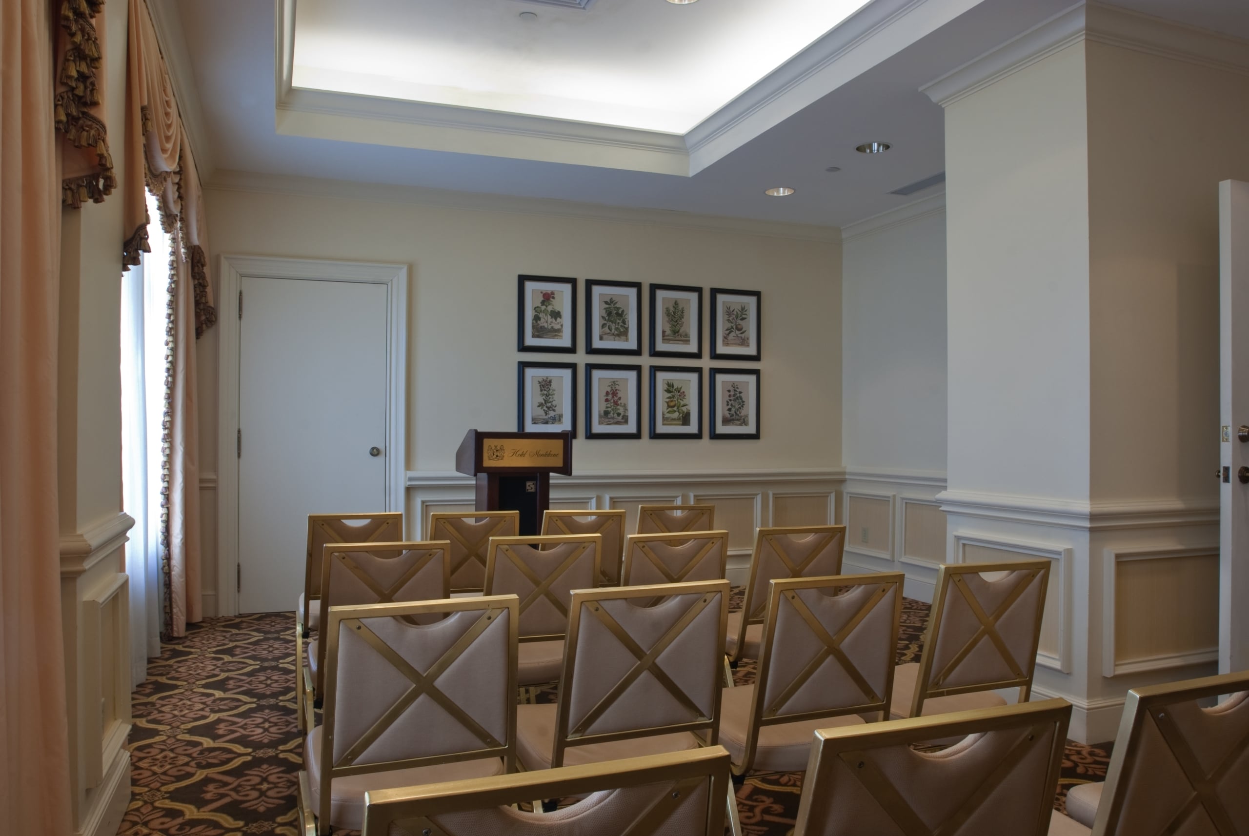 Hotel Monteleone conference room with elegant gold chairs, a podium, and ornate decor.