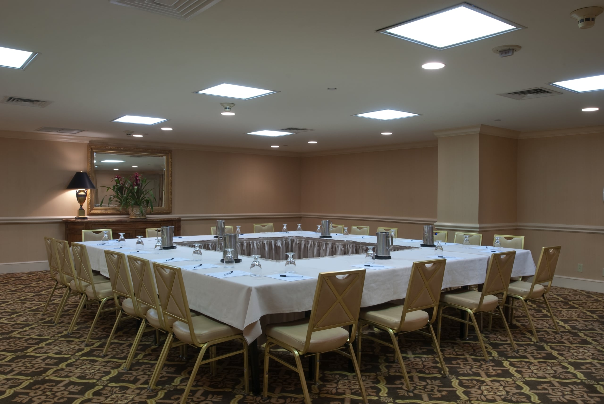 Spacious New Orleans hotel meeting room with a large square table setup and elegant decor.