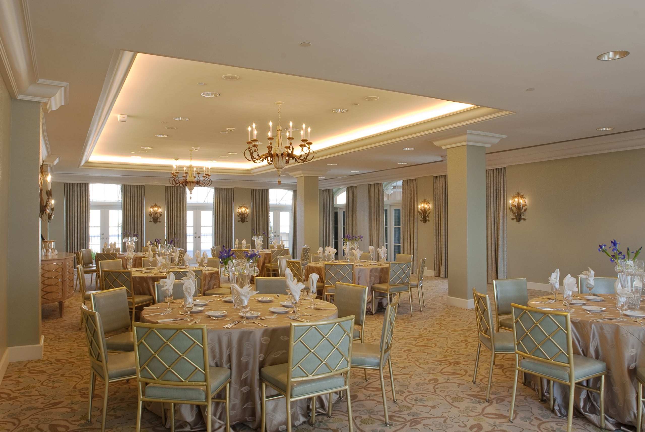 Luxurious New Orleans ballroom with elegant round tables, gold chairs, and ornate chandeliers.