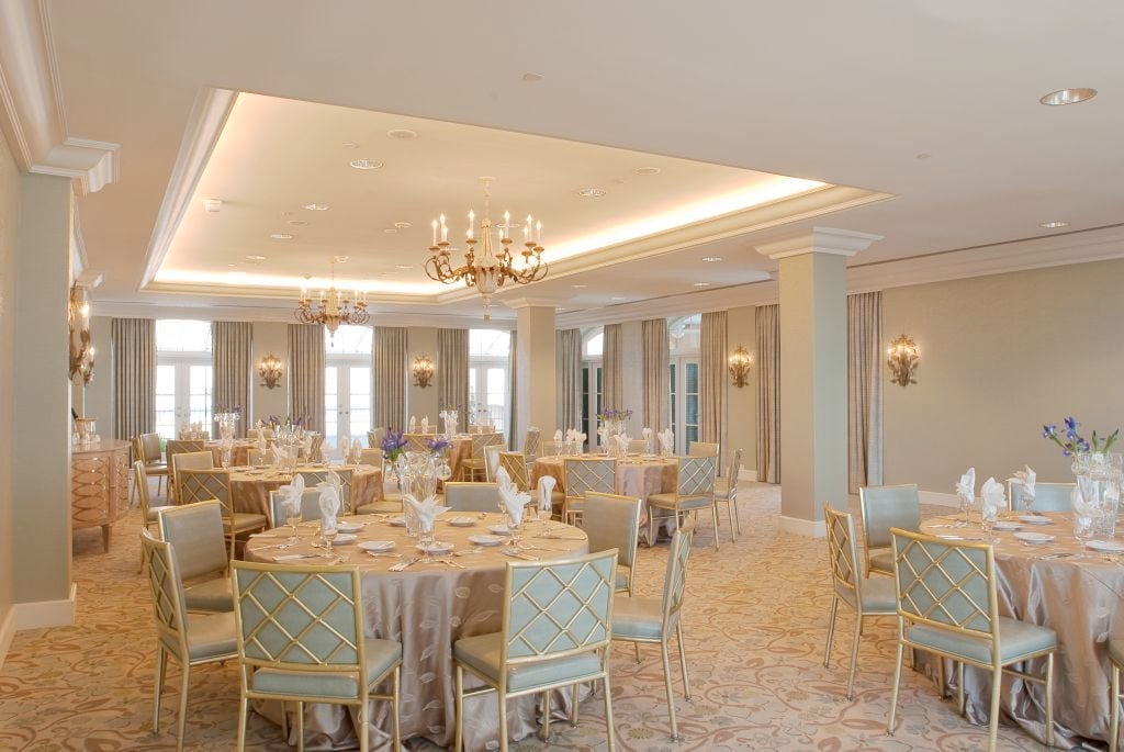 Luxurious New Orleans ballroom with elegant round tables, gold chairs, and ornate chandeliers.