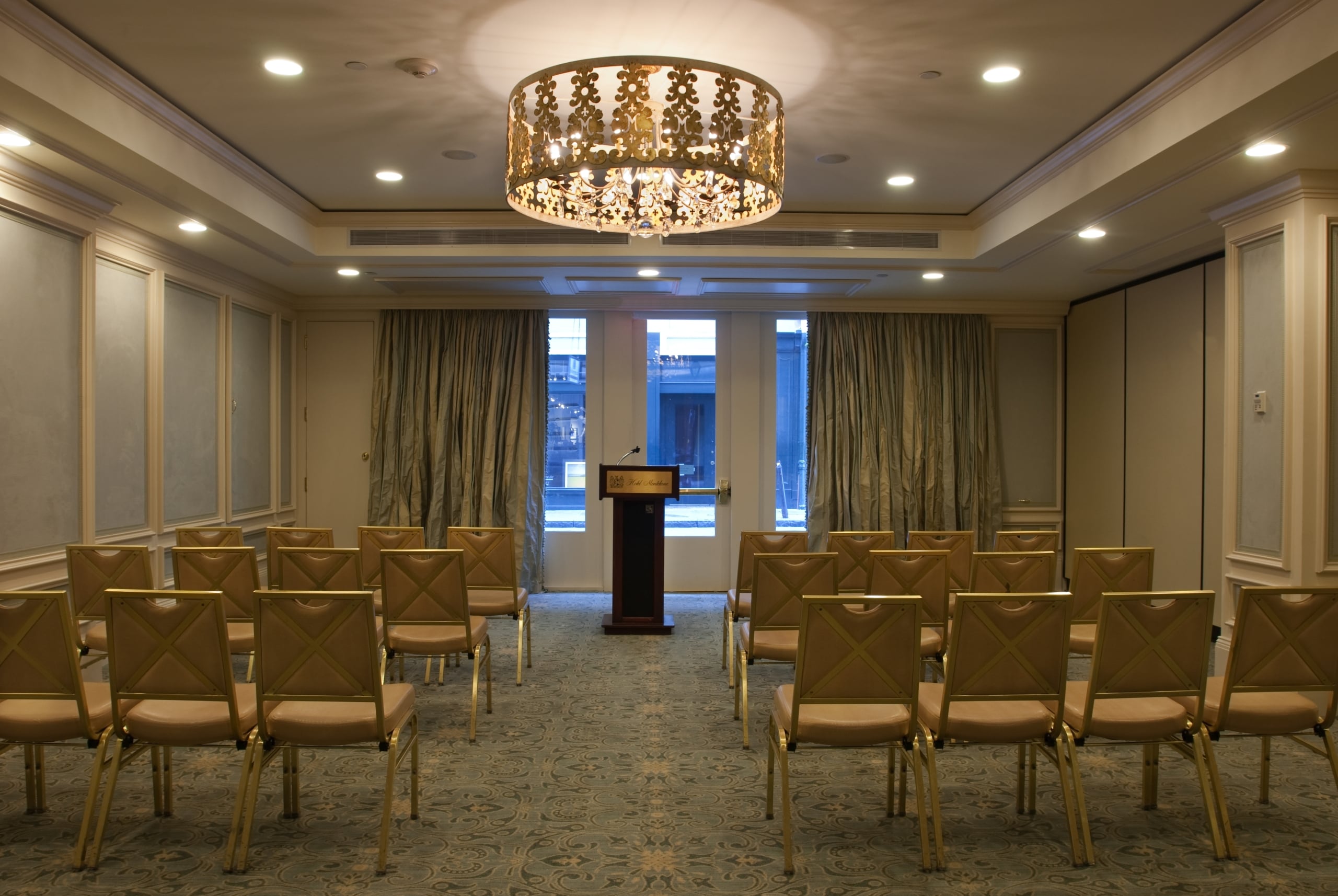 New Orleans Hotel Monteleone meeting room with formal chairs, a podium, and an ornate chandelier.