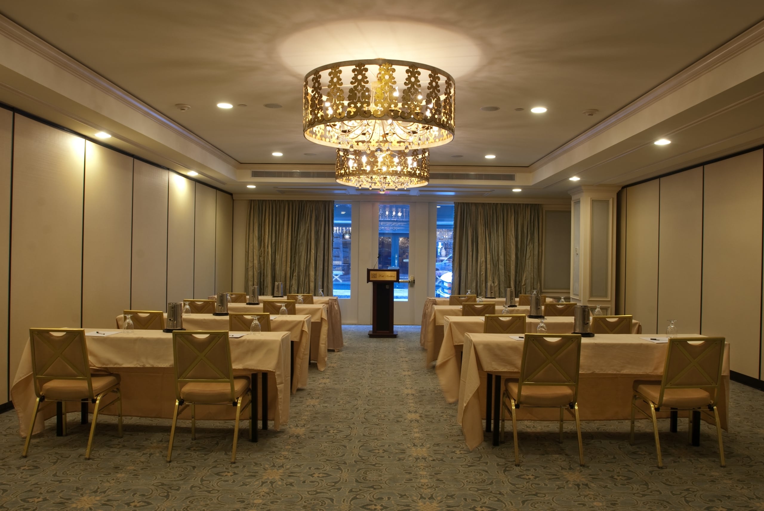 Elegant New Orleans hotel conference room with rows of tables, chairs, and two ornate chandeliers.