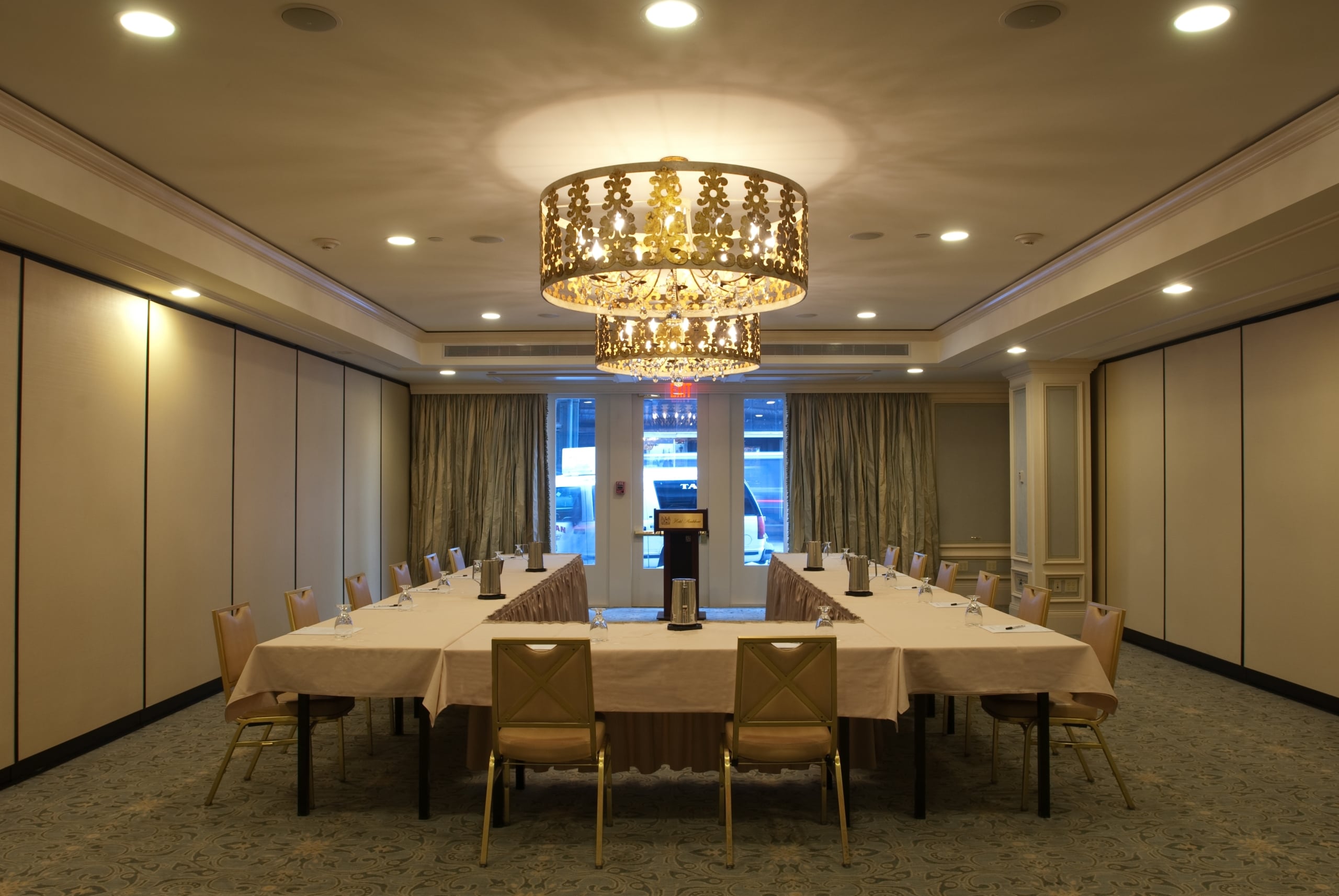 Elegant meeting room with a U-shaped table, gold chairs, and chandelier, ideal for events in New Orleans.