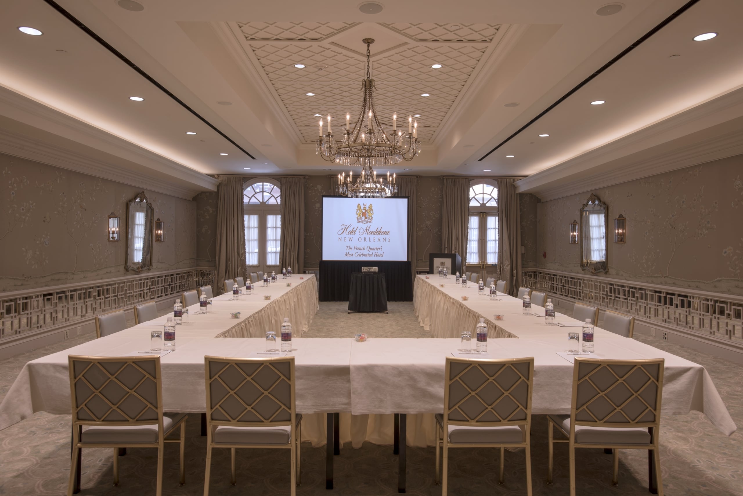 Hotel Monteleone New Orleans elegant meeting room with a U-shaped table, projector, and chandelier.