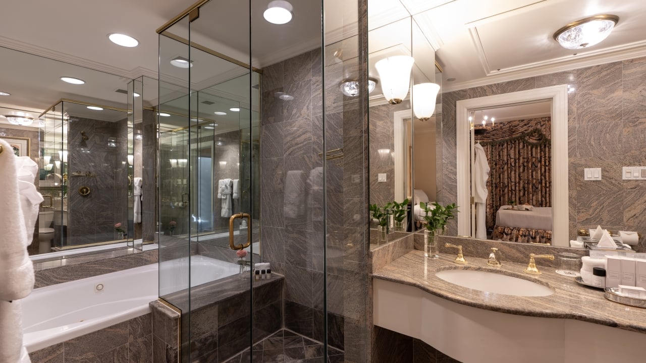 A luxurious bathroom with a large bathtub, glass-enclosed shower, and marble countertops.