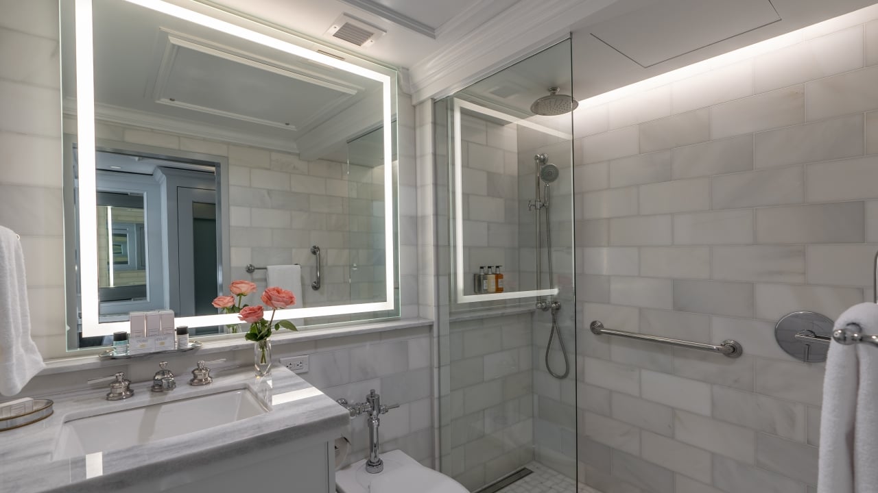 A clean and modern bathroom with a large mirror, sink, toilet, and shower.