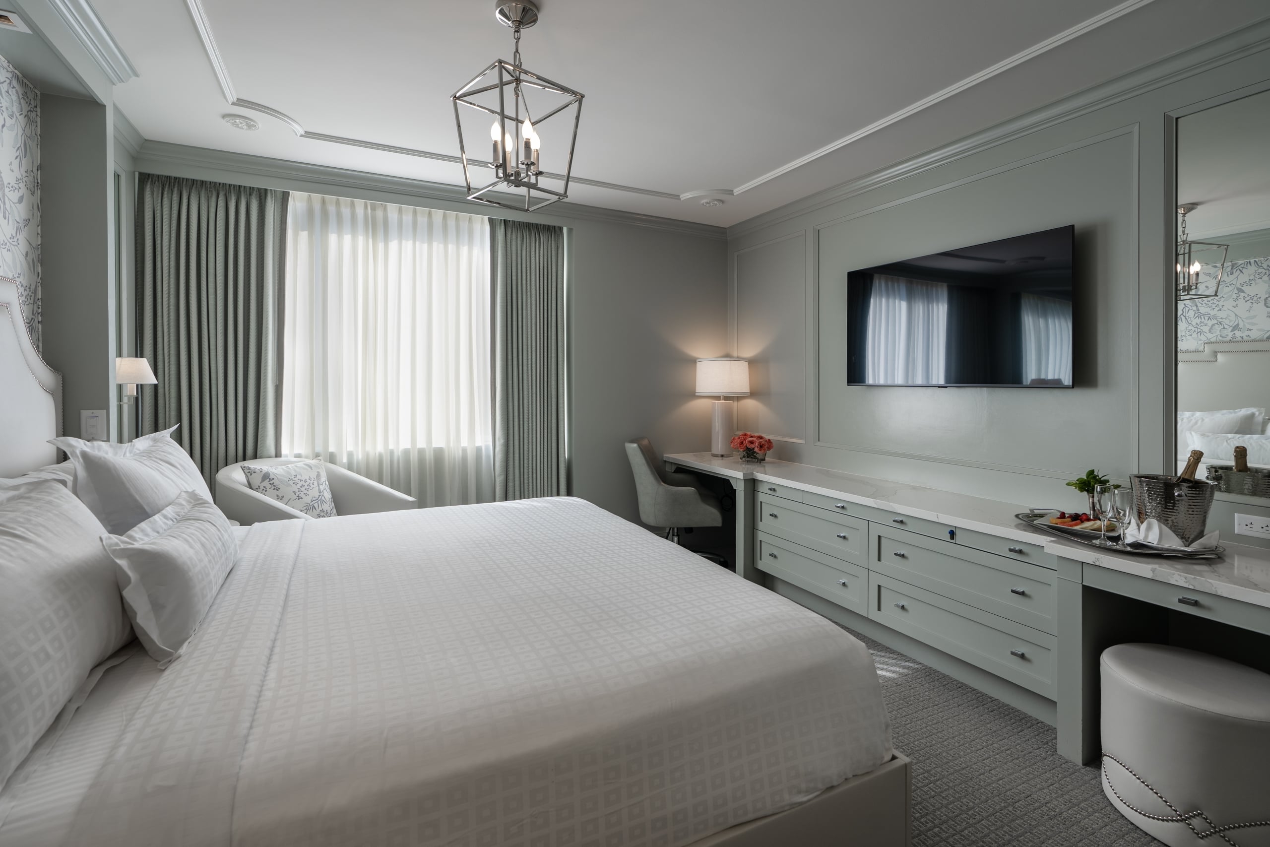 Elegant New Orleans hotel room with a king bed, subtle green walls, sophisticated decor, and a welcoming champagne setup.