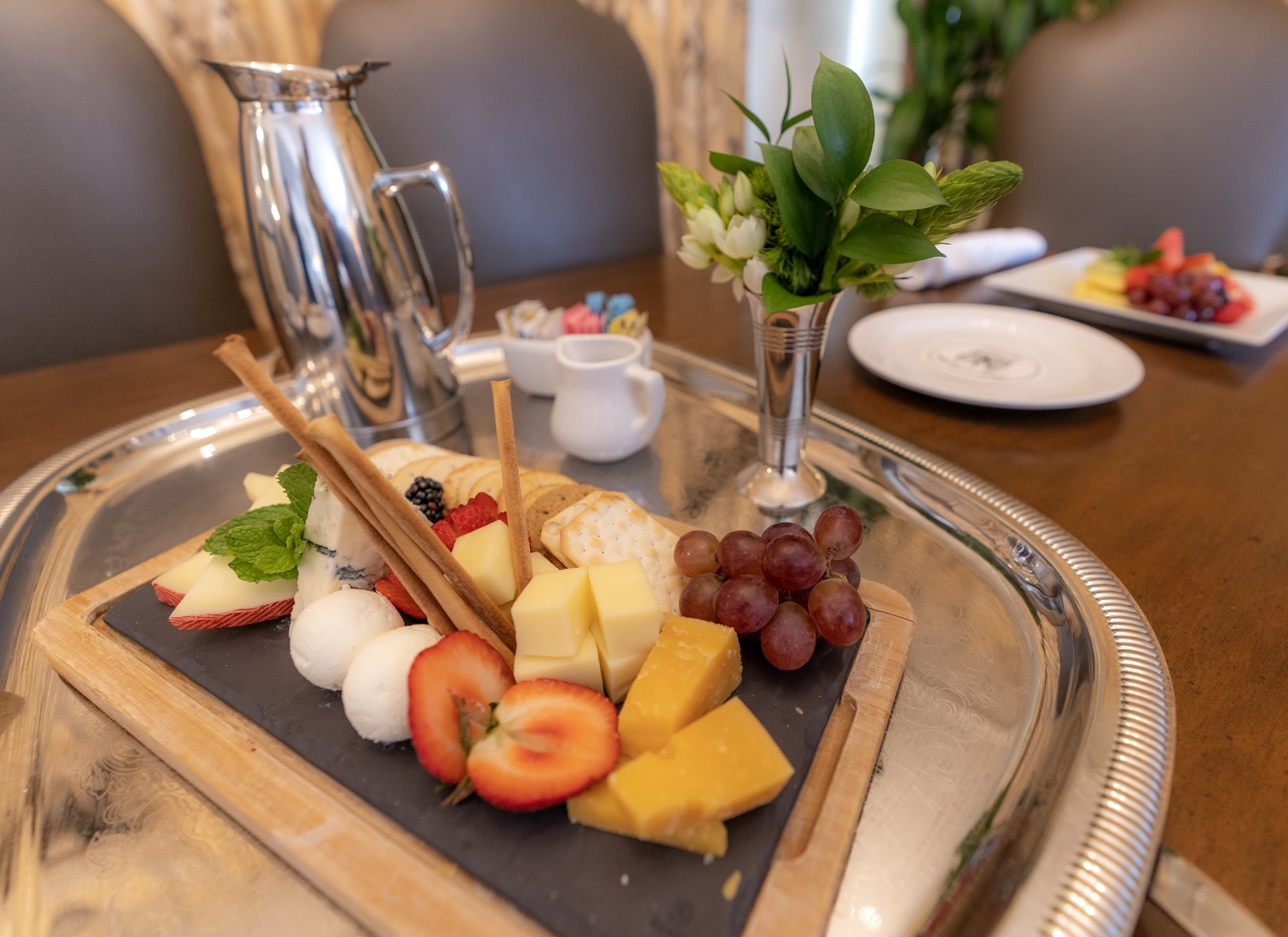 Gourmet cheese and fruit board with fresh berries, crackers, and a silver pitcher, perfect for a New Orleans stay.