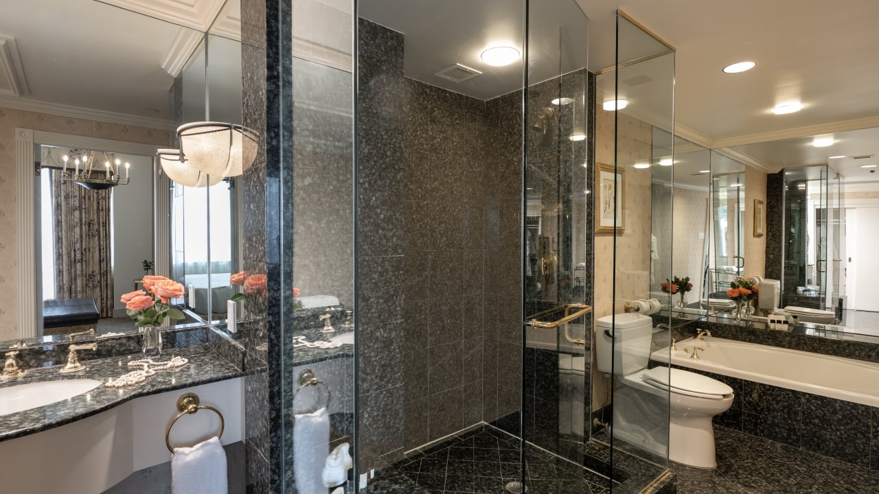 A luxurious bathroom with a large glass shower, granite countertops, and a soaking tub.