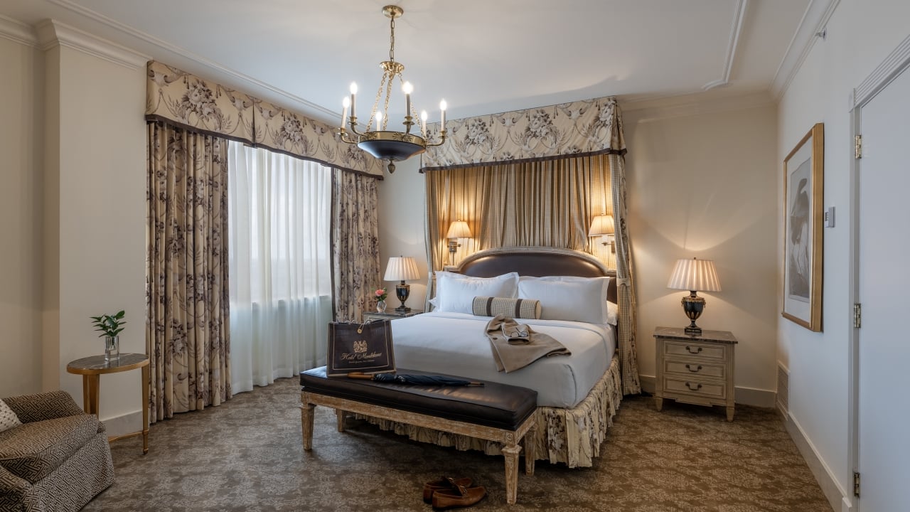 A luxurious hotel room with a large bed, chandelier, and window