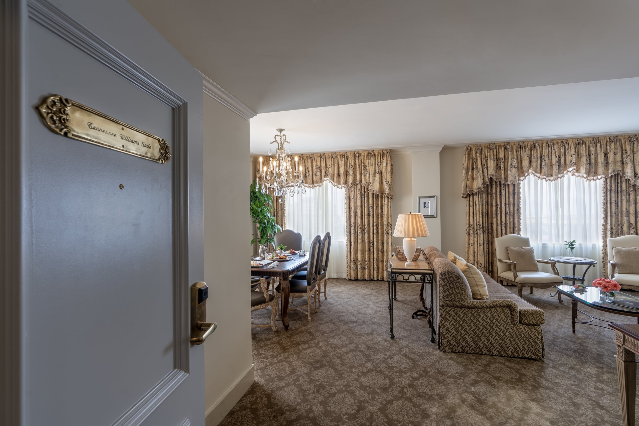 Open door revealing the luxurious Tennessee Williams Suite in New Orleans, with a dining and living area.