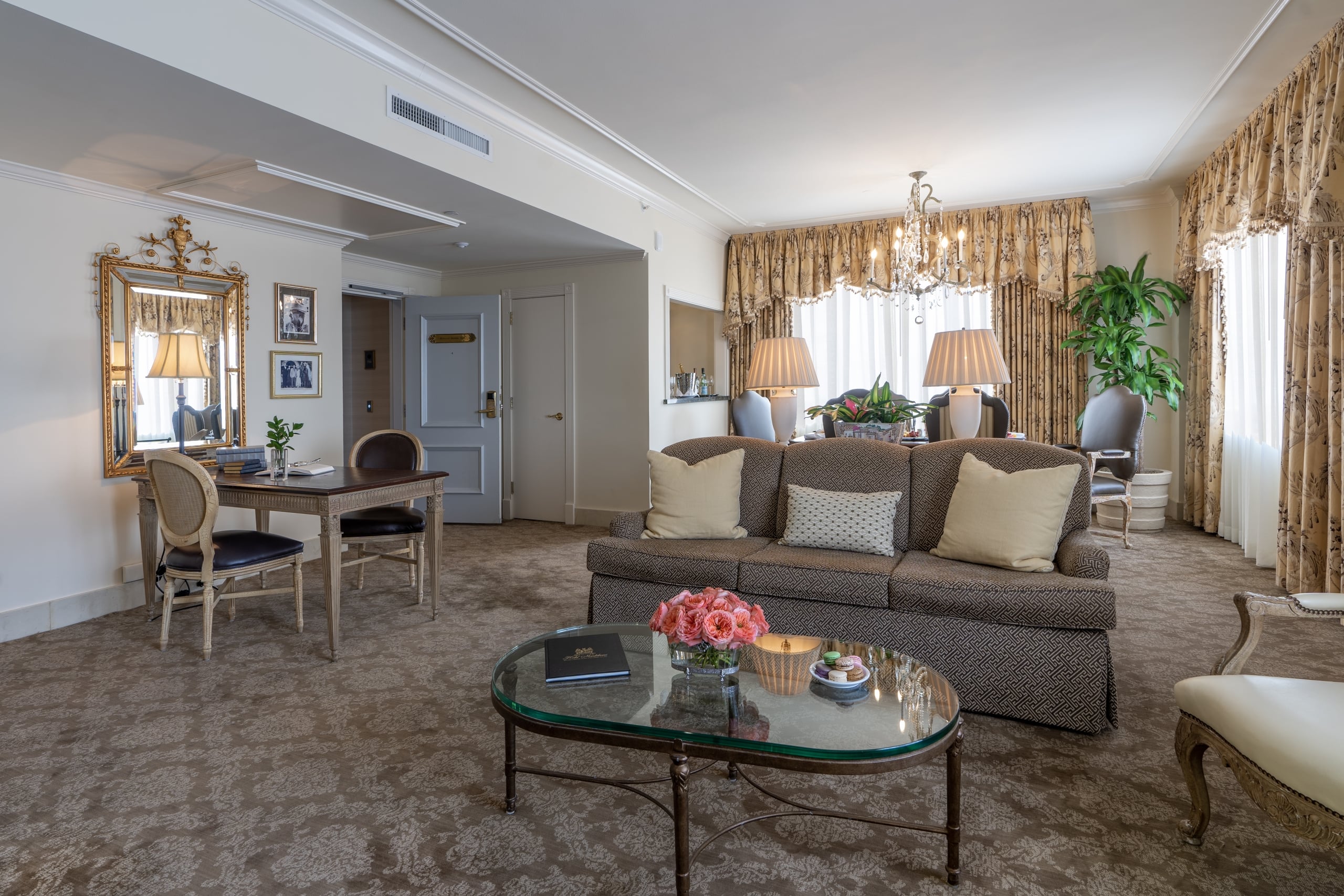 Elegant Hotel Monteleone suite living room featuring a classic sofa, desk, and ornate chandelier.