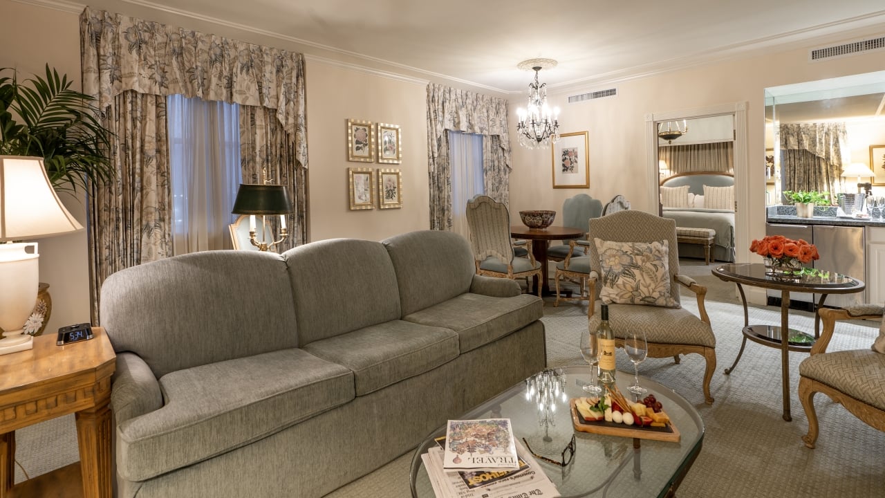 A wide view of a luxurious living room with a gray sofa, glass coffee table, and a dining area in the background.