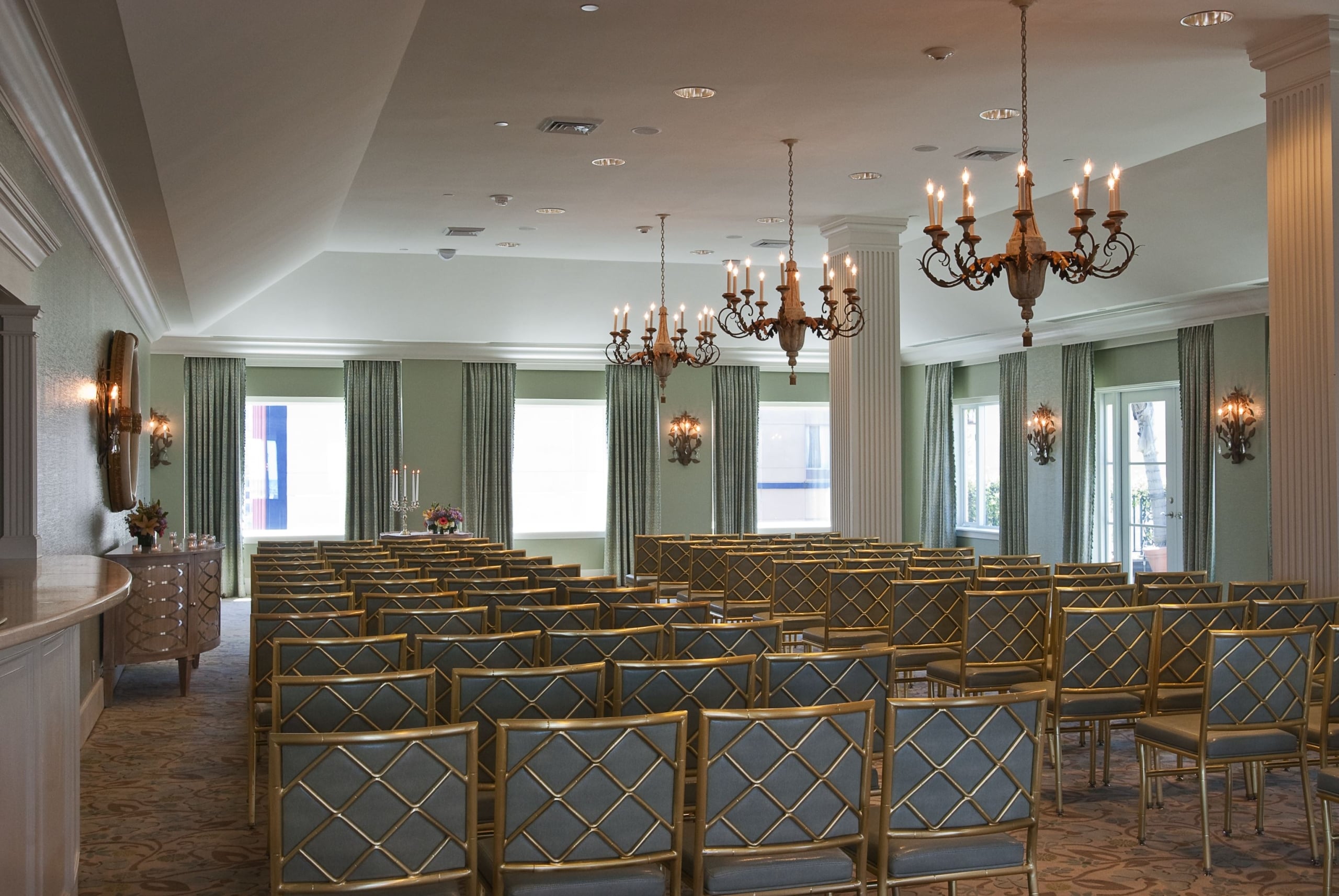 Elegant New Orleans event room set for a ceremony or meeting with gold chairs and ornate chandeliers.