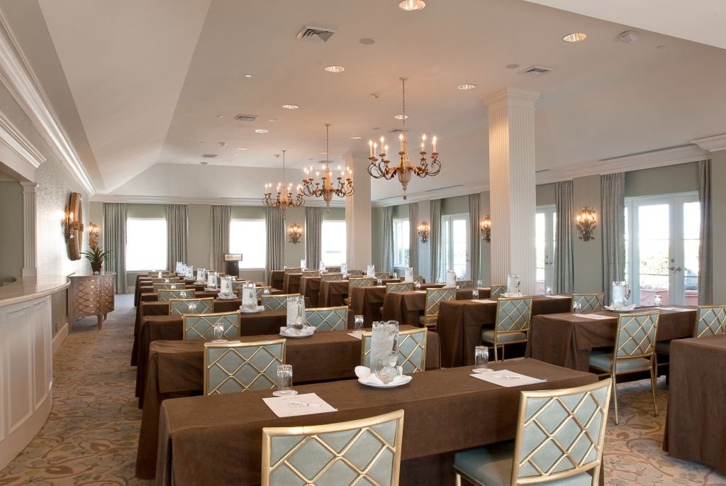 Elegant New Orleans ballroom set up for meetings, featuring chandeliers and brown draped tables.