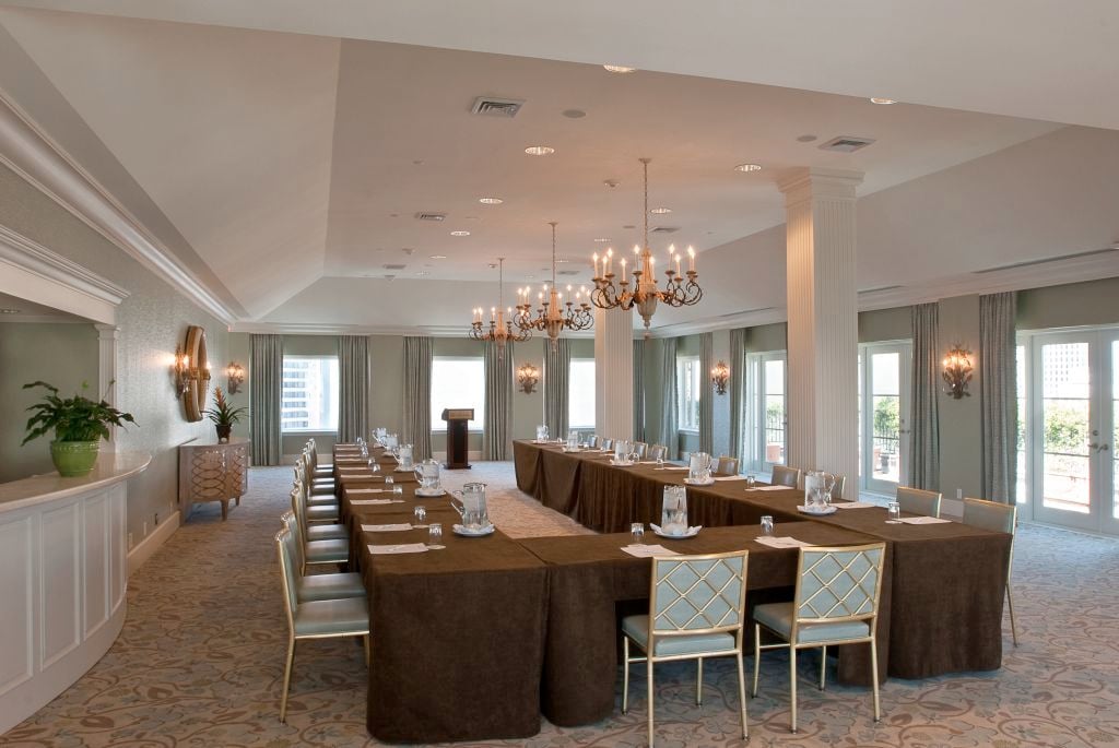 Elegant New Orleans hotel conference room with U-shaped tables, podium, and chandeliers.