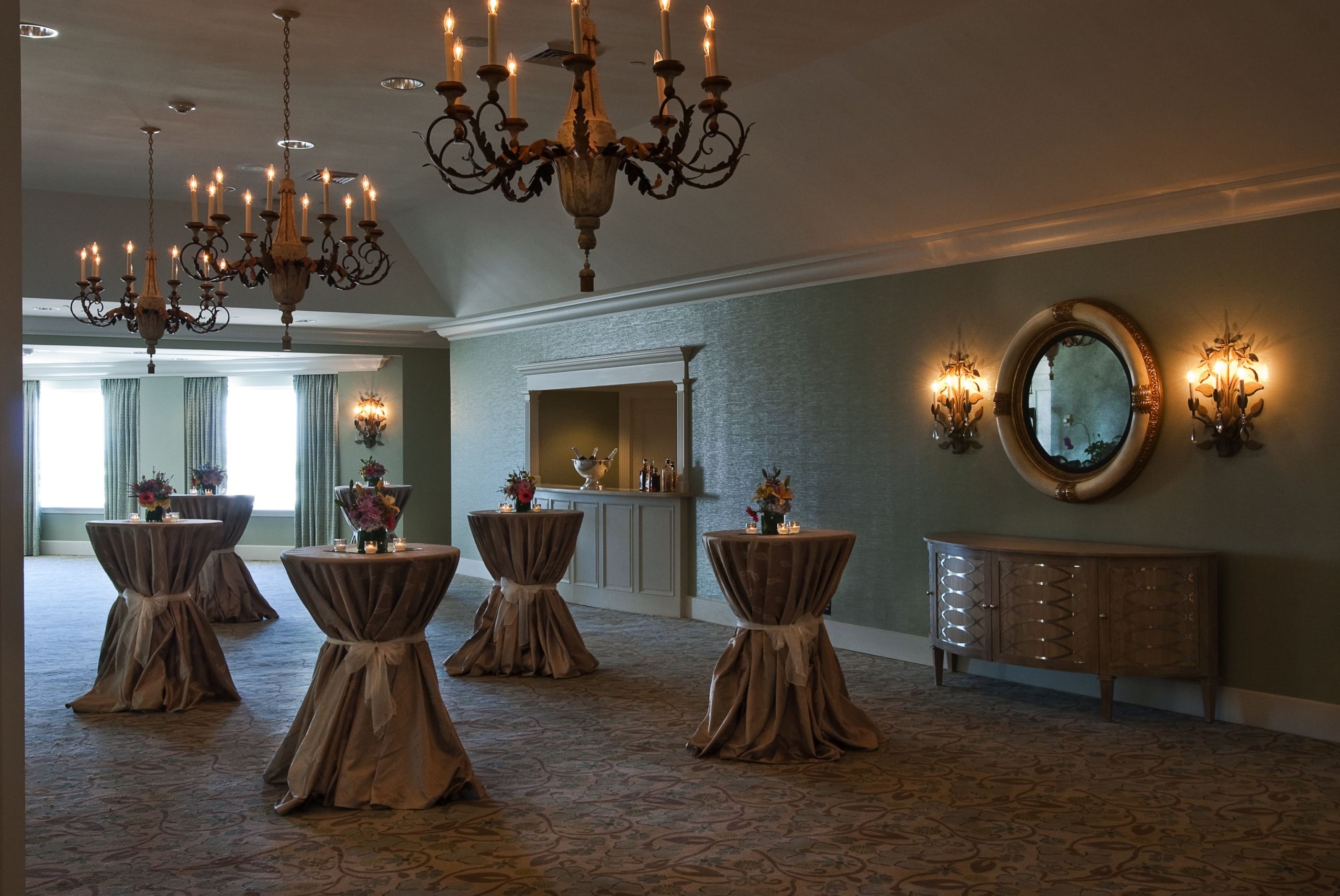 Grand New Orleans reception venue featuring ornate chandeliers, elegant cocktail tables, and a full bar.