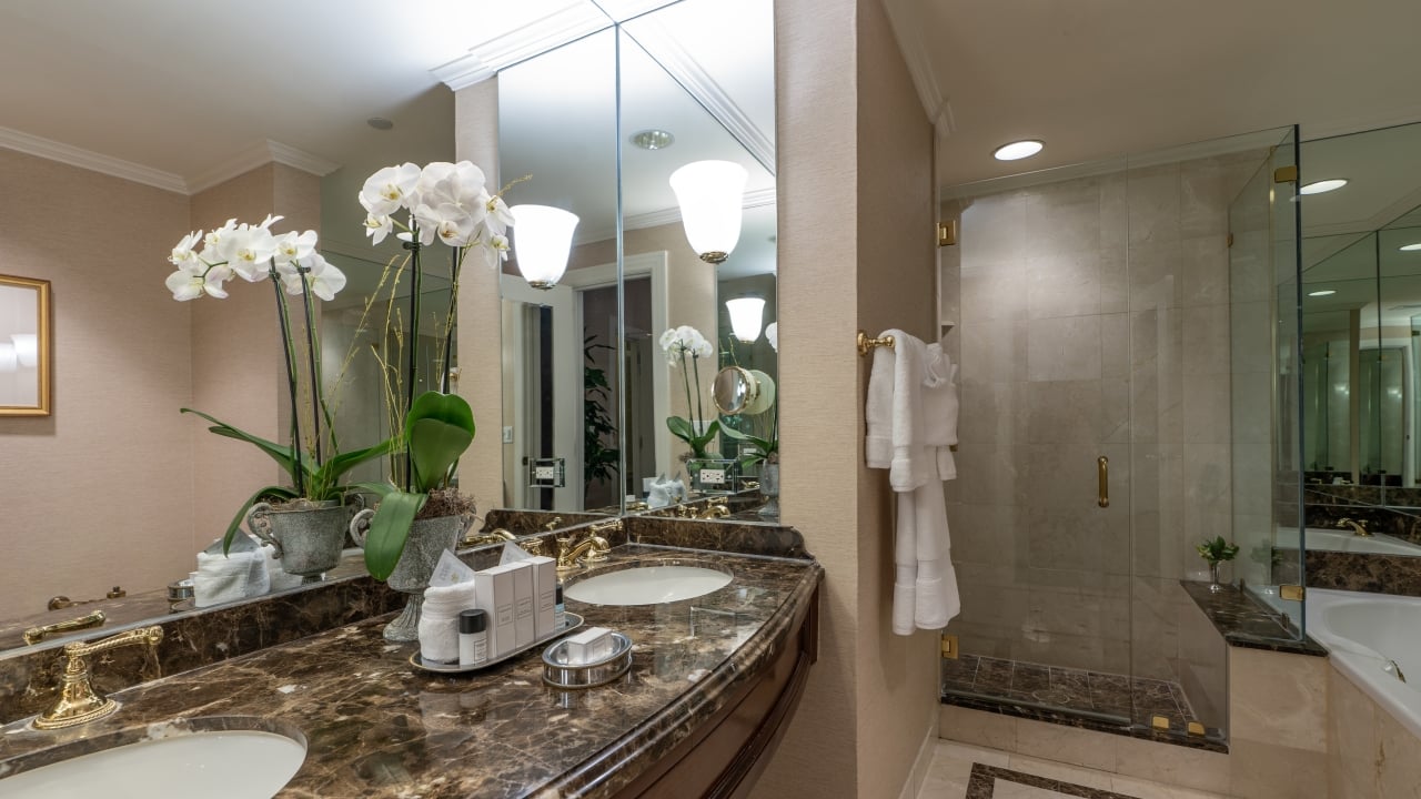 A luxurious bathroom with a double vanity, large mirror, glass-enclosed shower, and soaking tub.