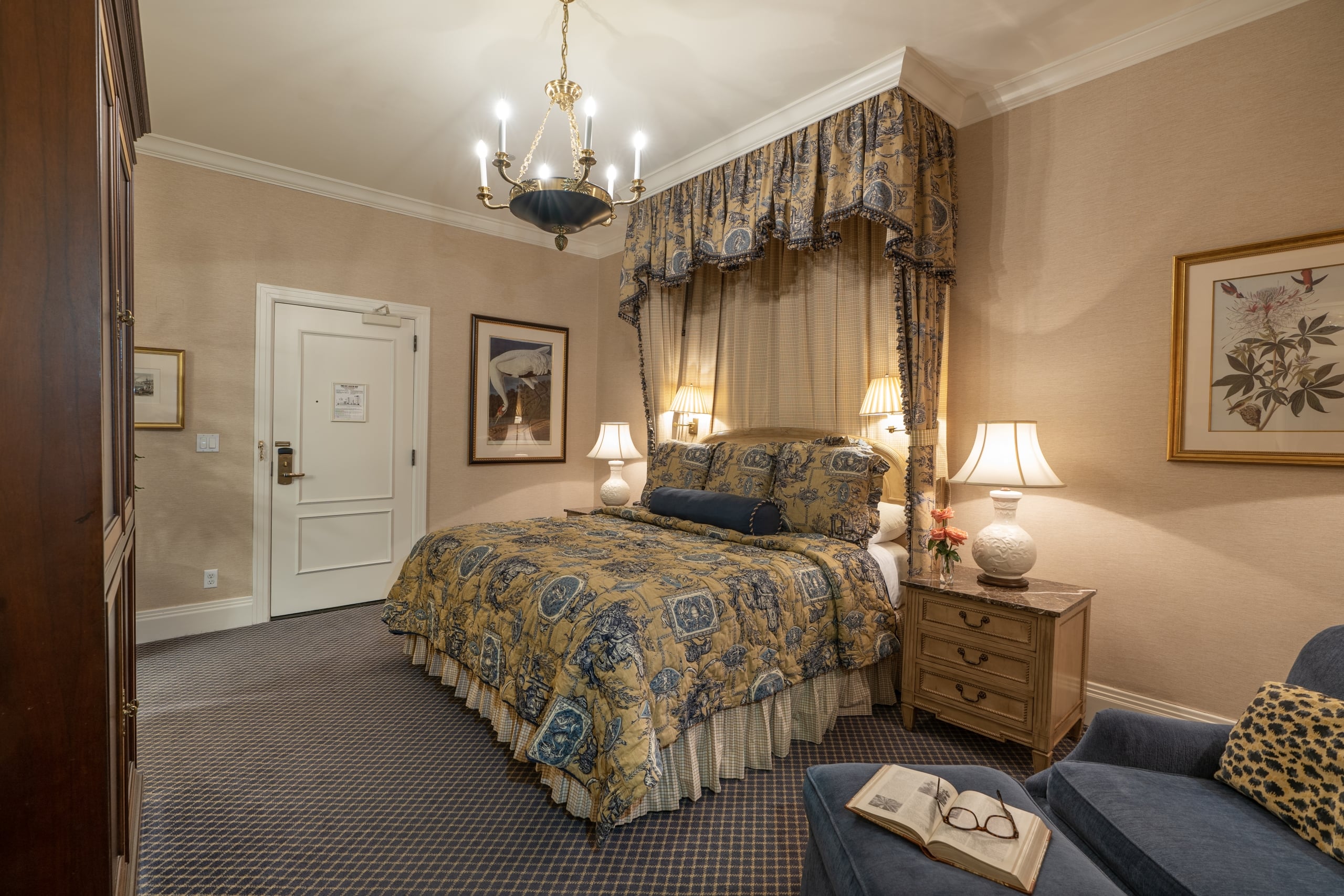 Elegant New Orleans hotel guest room with a lavish canopy bed, antique furniture, and classic decor.