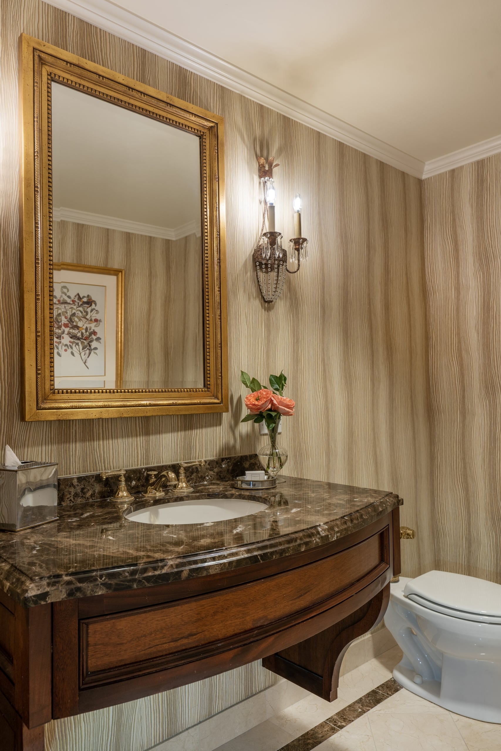 Luxurious hotel bathroom featuring a marble vanity, ornate gold mirror, and fresh roses in New Orleans.
