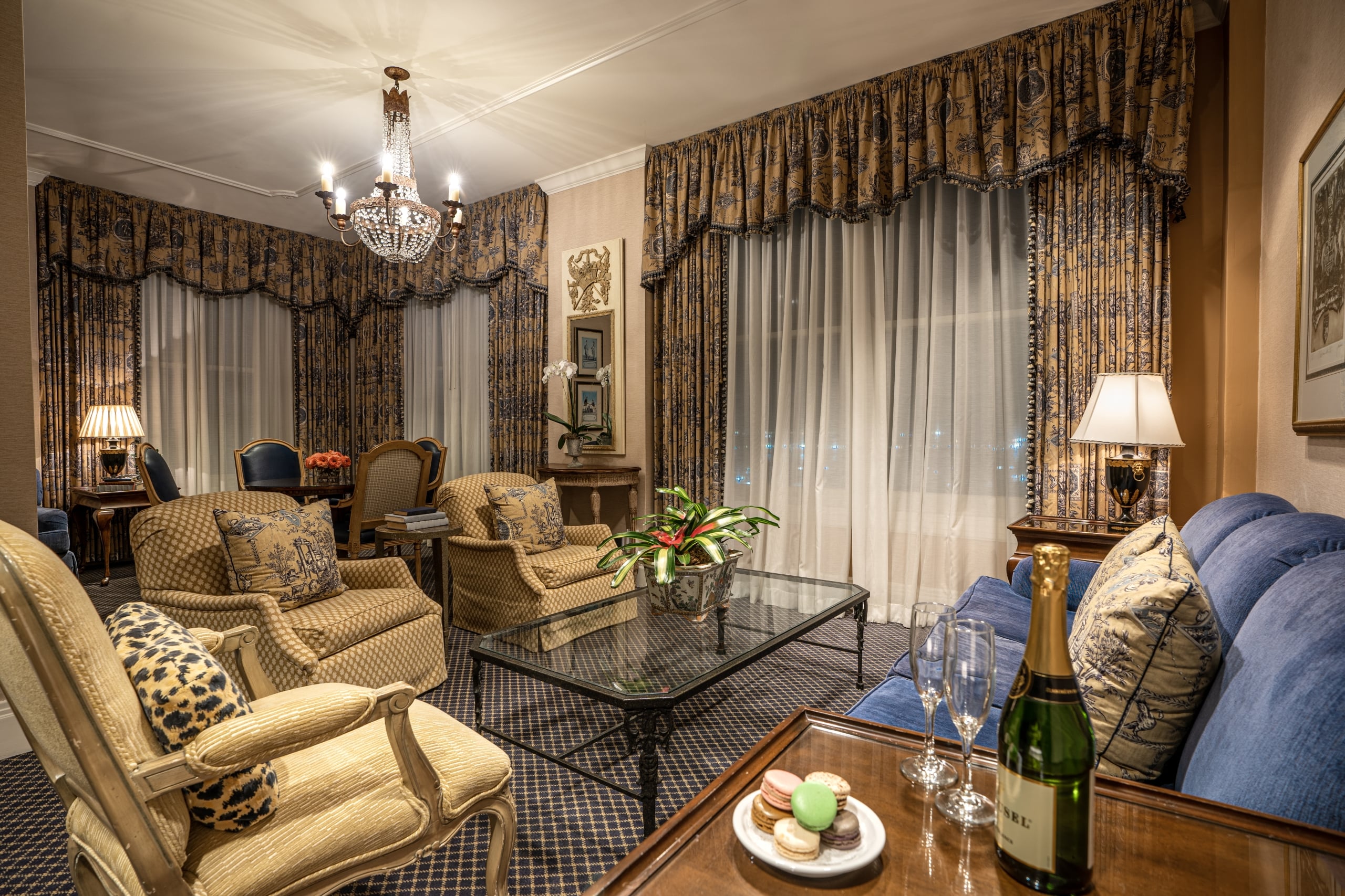 Luxurious New Orleans suite office with historic maps, a glass desk, and blue leather chair.
