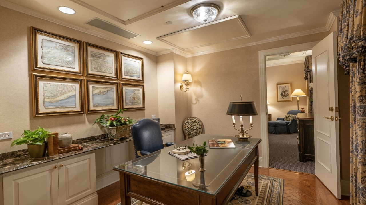 A well-appointed office with a large desk, comfortable seating, and decorative artwork.
