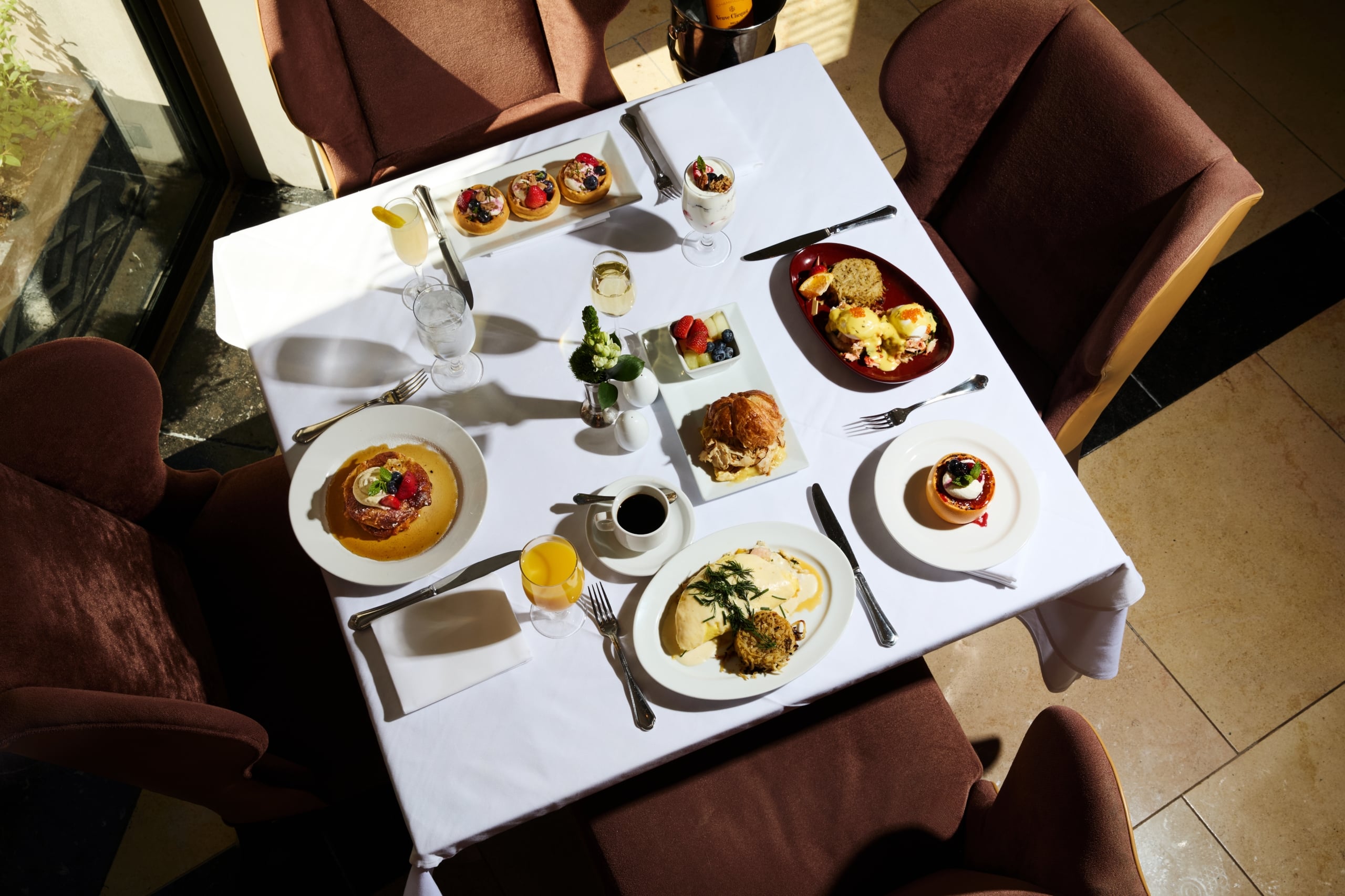 Gourmet brunch table with eggs benedict, fruit tarts, and mimosas in New Orleans.